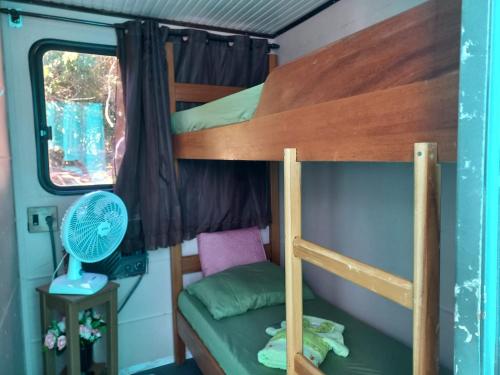 a bunk bed in a tiny house with a fan at Barco Casa Pantanal Toca da Onça in Poconé