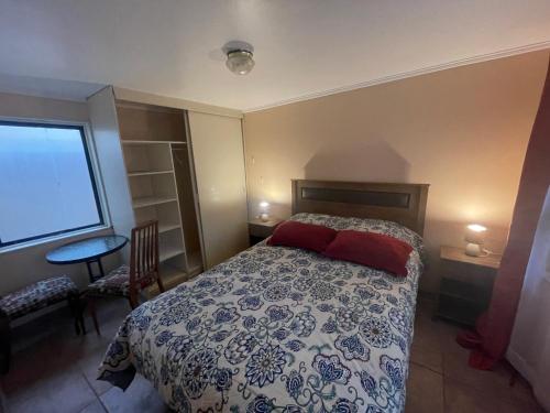 um quarto com uma cama, uma mesa e uma janela em Hostal EntreOrientes em Viña del Mar