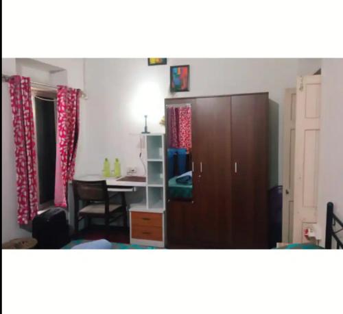 Habitación con escritorio, armario y mesa. en Happy Home, en Calcuta