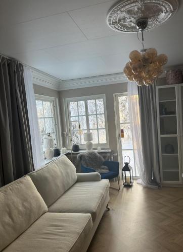 uma sala de estar com um sofá e um lustre em Lugnet em Skebobruk