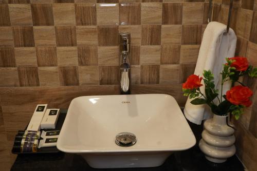 a bathroom with a sink and a phone and flowers at Swet Palash Resort in Purulia