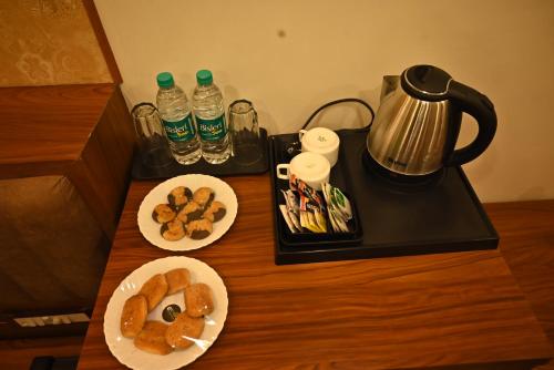 a table with two plates of pastries and water bottles at Swet Palash Resort in Purulia