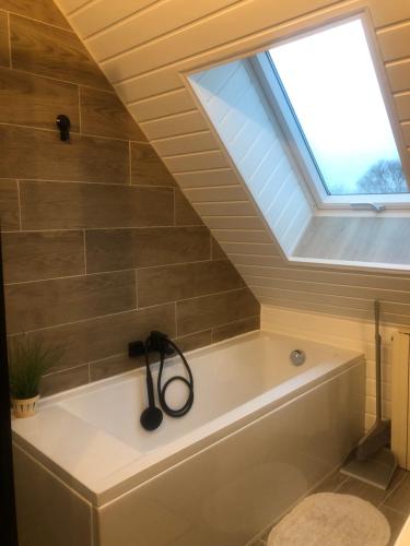 uma casa de banho com uma banheira e uma clarabóia em Le Relais du Biau Ri em Clairfayts