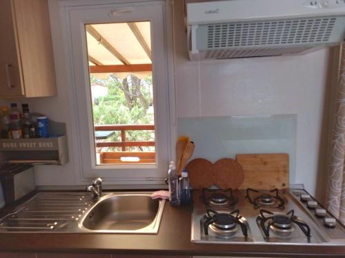 a kitchen with a sink and a stove and a window at Camping, mobil home équipé proche du lac de Sainte Croix et des gorges du Verdon in Sainte-Croix-de-Verdon