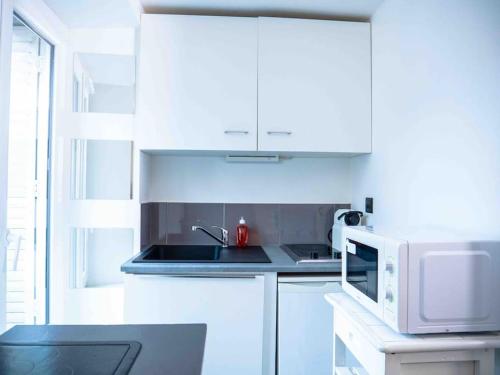 une cuisine blanche avec un évier et un micro-ondes dans l'établissement Studio Charles 3 hypercentre, à Nancy