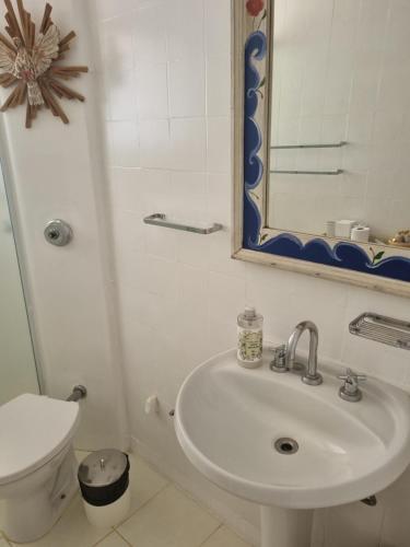 een badkamer met een wastafel, een toilet en een spiegel bij Casa no Condomínio Vila Pinhal na represa do Broa. in Itirapina