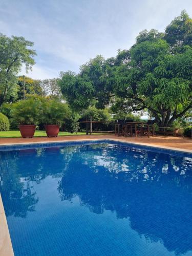 une grande piscine bleue avec des arbres en arrière-plan dans l'établissement Casa no Condomínio Vila Pinhal na represa do Broa., à Itirapina