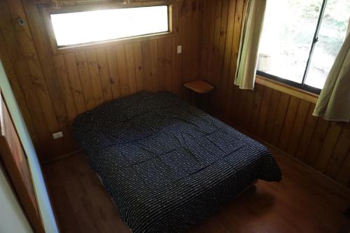 a small bed in a room with a window at Cabaña compartida en santuario de la naturaleza Rio Cutipay in Valdivia