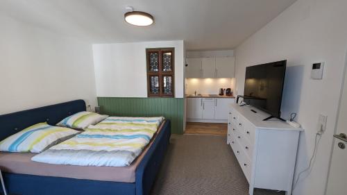 um pequeno quarto com uma cama e uma televisão em Gästezimmer Michelskeller em Sulzfeld am Main
