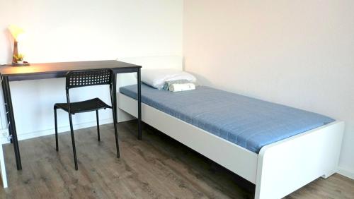 ein kleines Schlafzimmer mit einem Schreibtisch und einem Bett mit einem Stuhl in der Unterkunft Apartkeep Chemnitz 234 in Chemnitz