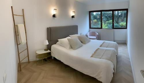 a bedroom with a large white bed and a window at Magnifique Appartement, 3 min de Paris in Levallois-Perret
