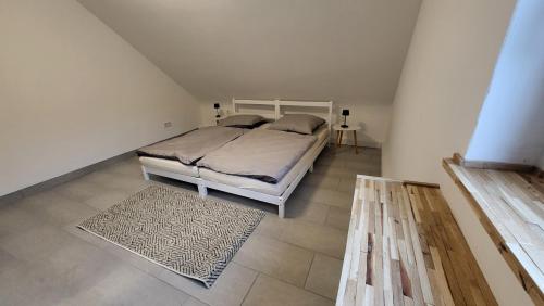 a bedroom with a white bed and a rug at Ferienwohnung am Grumbach in Saarbrücken