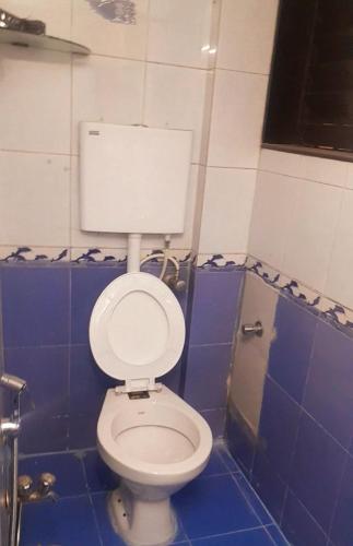 a bathroom with a white toilet in a blue tiled room at Stay in elegant 1bhk in Navi Mumbai