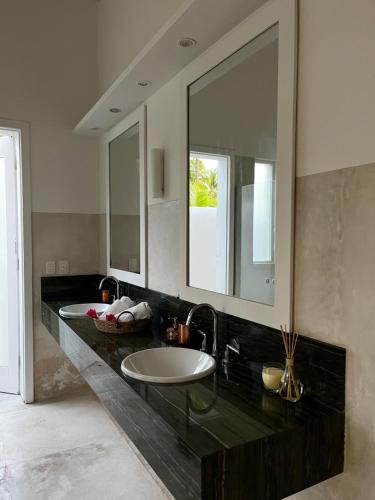 Maxaranguape的住宿－Maracajau Luxury Home - Villa-Mar-a-Villa，一间带两个盥洗盆和大镜子的浴室