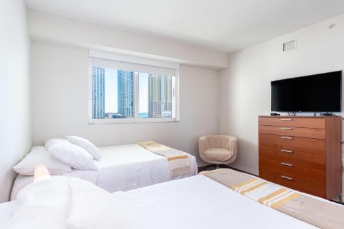 a bedroom with two beds and a flat screen tv at Marina Bay 113 in Miami Beach