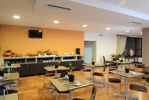 a restaurant with tables and chairs and a tv on a wall at ARAMI HOTEL & LODGE in Puerto Iguazú