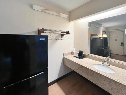 a bathroom with a sink and a black refrigerator at Studio 6 Suites Shreveport, LA Industrial Loop in Shreveport