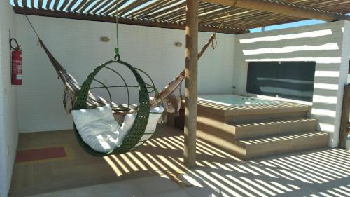 a hammock hanging from a porch with a tv at Pousada Solarium in Canoa Quebrada