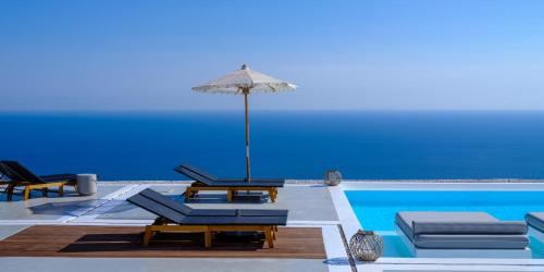 una piscina con sillas y una sombrilla junto a una piscina en Terra Blanca Suites en Imerovigli
