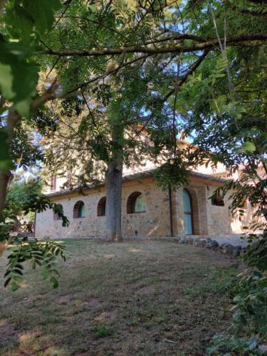 a stone house with a tree in front of it at Fattoria Agriturismo Nerbona in Casole dʼElsa