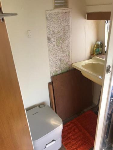 a small bathroom with a toilet and a sink at The Mighty Atom - 1976 2 berth Safari Retro Caravan in Abergavenny