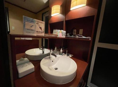 uma casa de banho com um lavatório branco e um espelho. em アルカディア em Maizuru