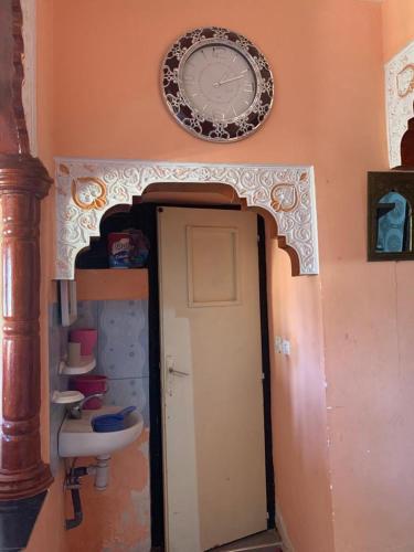 uma casa de banho com um lavatório e um relógio na parede em Grand Atlas Guesthouse 44 km from Marrakech em Marrakech