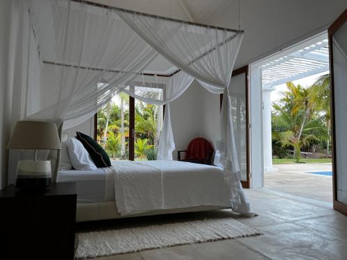 1 dormitorio con 1 cama blanca con dosel en Maracajau Luxury Home - Villa-Mar-a-Villa en Maxaranguape