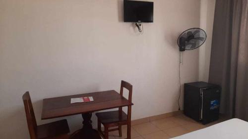 Zimmer mit einem Schreibtisch, einem Tisch und einem Ventilator in der Unterkunft RAOOF HOTEL in Mahajanga