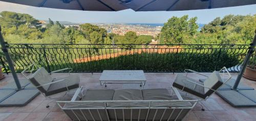 un patio avec des chaises, une table et un parasol dans l'établissement Apartment with sea/city views, near downtown Sète, à Sète