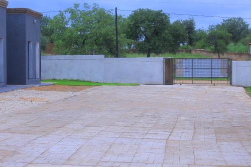 an empty parking lot with a fence and a brick sidewalk at Lis ville guest house in Phalaborwa