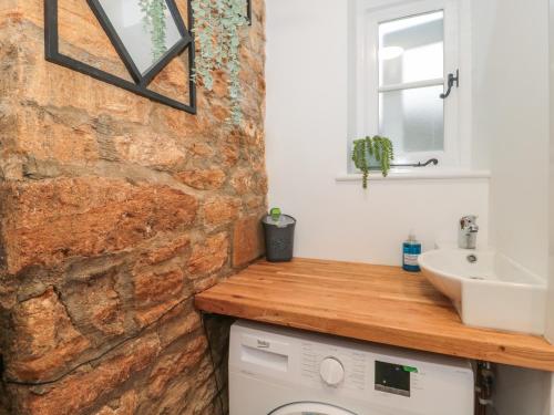 a bathroom with a sink and a stone wall at Two Towers Cottage in Montacute