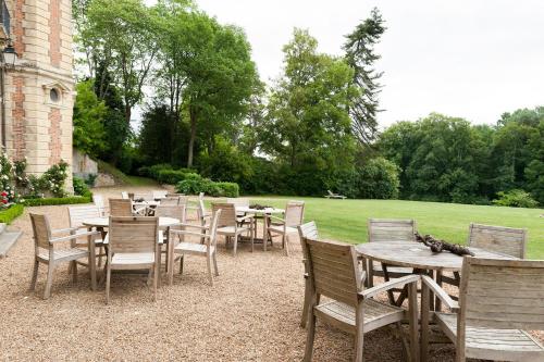 a row of wooden tables and chairs in a yard at Château de Perreux, The Originals Collection in Amboise