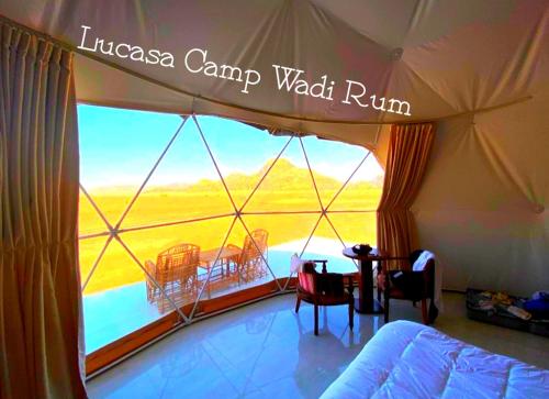 a bedroom with a large window with a table and chairs at Lukasa camp Wadi Rum in Wadi Rum
