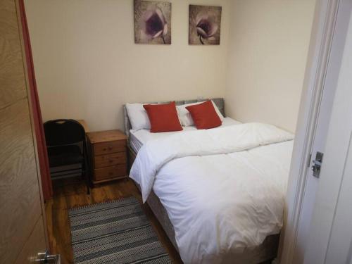 - une chambre avec 2 lits et des oreillers rouges dans l'établissement NightRest Homes 5 Bedroom House - Smart Tv in Each Room-Parking-Wifi, à Welwyn Garden City