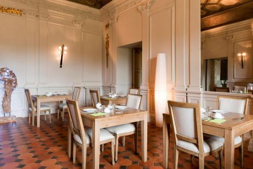 a dining room with wooden tables and chairs at Château de Perreux, The Originals Collection in Amboise
