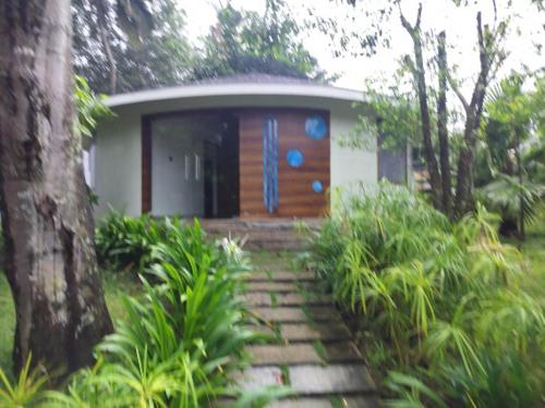 Una pequeña casa con una puerta de madera en un jardín en Michael Leisure & Ayurveda Retreat, en Trivandrum