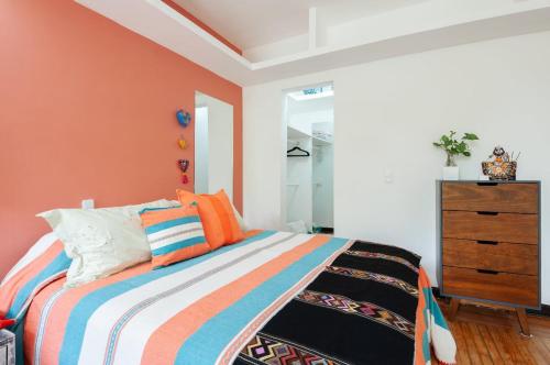 a bedroom with a bed with orange walls and a dresser at Casa Itzae B&B Polanquito Dog Friendly in Mexico City