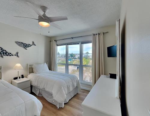 a white bedroom with two beds and a window at Madeira Beach Yacht Club 247f in St Pete Beach