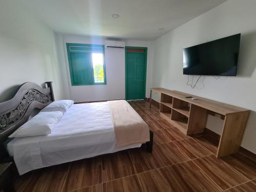 Dormitorio con cama, escritorio y TV en LA ALBACEA, en Quimbaya