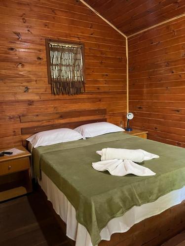1 dormitorio con 1 cama con 2 toallas en Pousada Árvore Centenária, en São Thomé das Letras