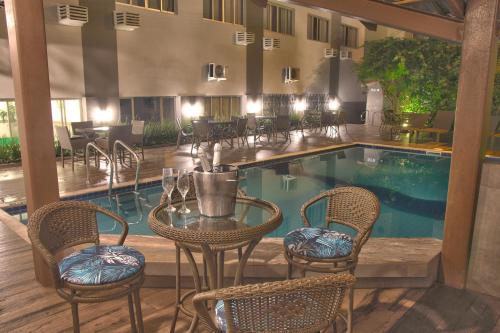 a hotel with a pool and tables and chairs at Hotel Gracher Praia in Balneário Camboriú