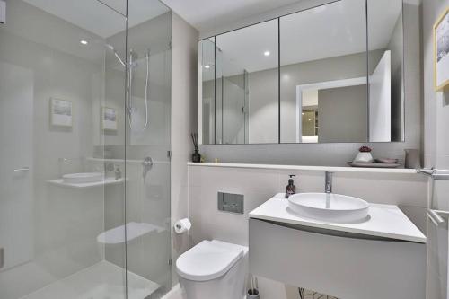 a bathroom with a toilet and a sink and a shower at Chic Zenith Retreat -Vista, Skylight, Parking in Sydney