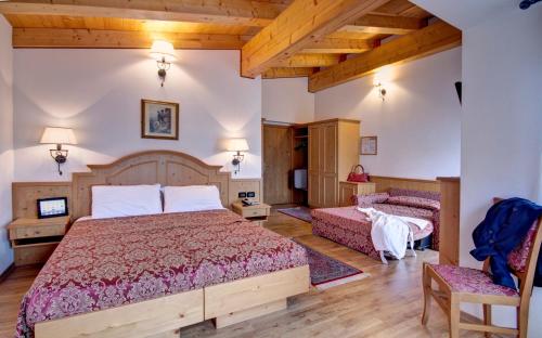 una camera con due letti in una stanza con soffitti in legno di Hotel Des Alpes a Cortina dʼAmpezzo