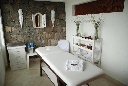 Habitación con mesa blanca y pared de piedra. en Pousada Singuitta - Ilhabela en Ilhabela