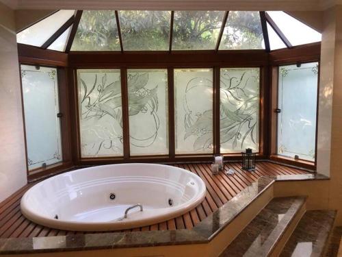 eine große Badewanne in einem Zimmer mit Fenstern in der Unterkunft Casa na Serra incrivel com vista para as montanhas in Petrópolis