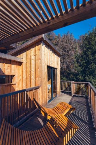 a wooden cabin with a wooden deck with a bench at LES CABANES DE LUTINA in Poggio-Marinaccio