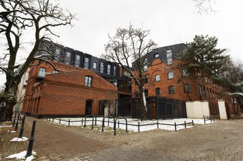 duży ceglany budynek z płotem przed nim w obiekcie KM RENT Łódź, Kopernika 15 w Łodzi