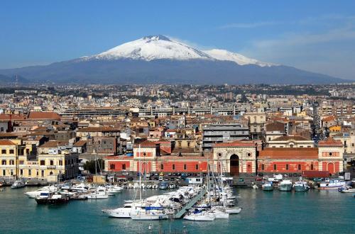 eine Stadt mit einem Berg im Hintergrund mit Booten im Hafen in der Unterkunft Gesuiti Home di Agata e Aurora in Catania