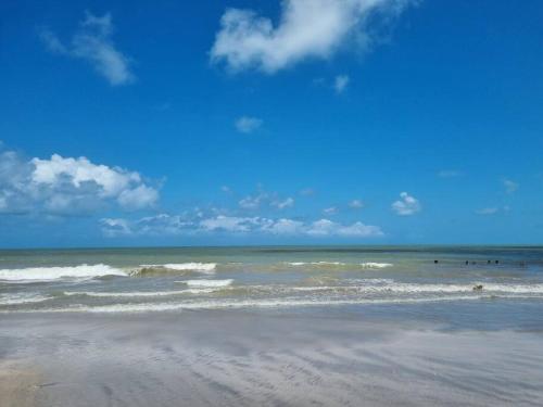 a beach with waves and people in the ocean at Espaço Sol e Mar - Praia Azul/PB in Pitimbu